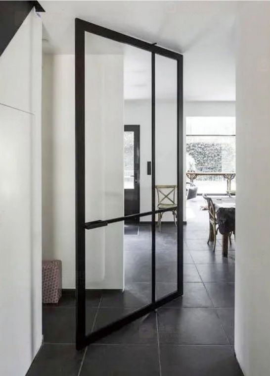 Black steel-look aluminum pivot door separating hallway from dining area.