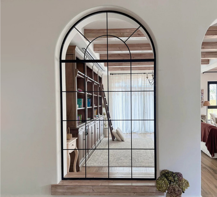 Custom Arched Pivot Door with black aluminum frame and French-style glass grid design.